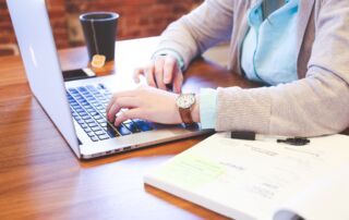 Student working on a laptop beside an open notebook.