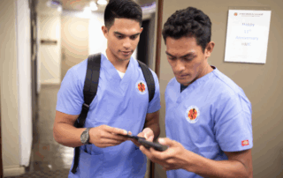 Hawaii Medical College students in scrubs reviewing information together, highlighting tips on building a professional network while still in school.