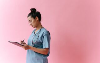 Hawai‘i healthcare student in scrubs writing on clipboard, representing top traits employers seek in 2025 for medical careers